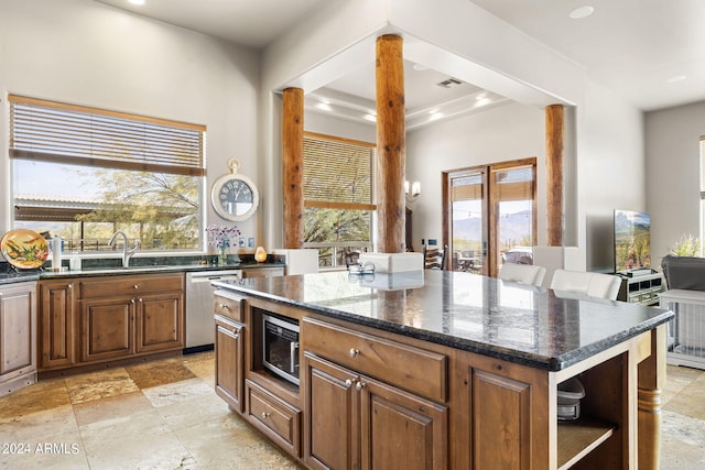 kitchen with appliances with stainless steel finishes, a kitchen island, dark stone countertops, and a wealth of natural light