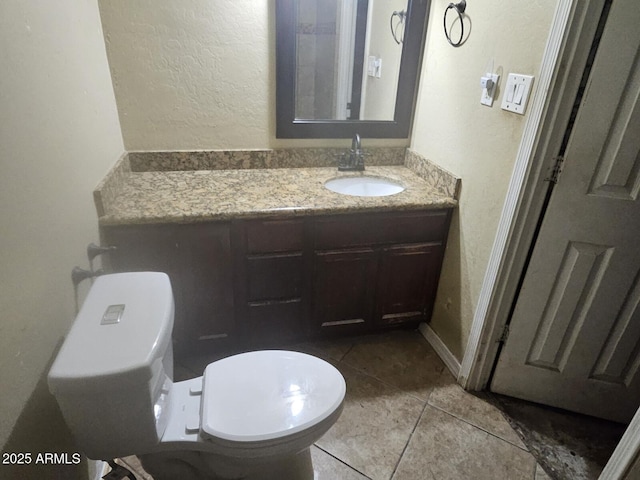 bathroom featuring toilet, tile patterned flooring, vanity, and a textured wall