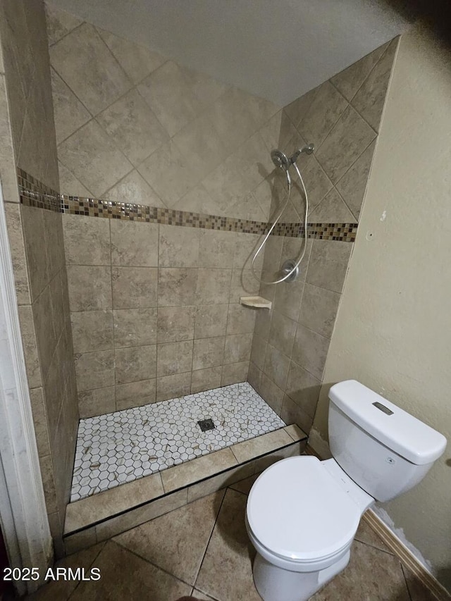 full bath with toilet, a stall shower, and tile patterned flooring