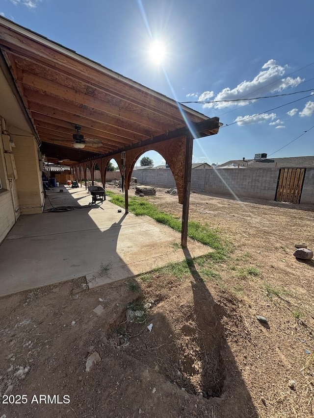 fenced backyard with a ceiling fan and a patio area