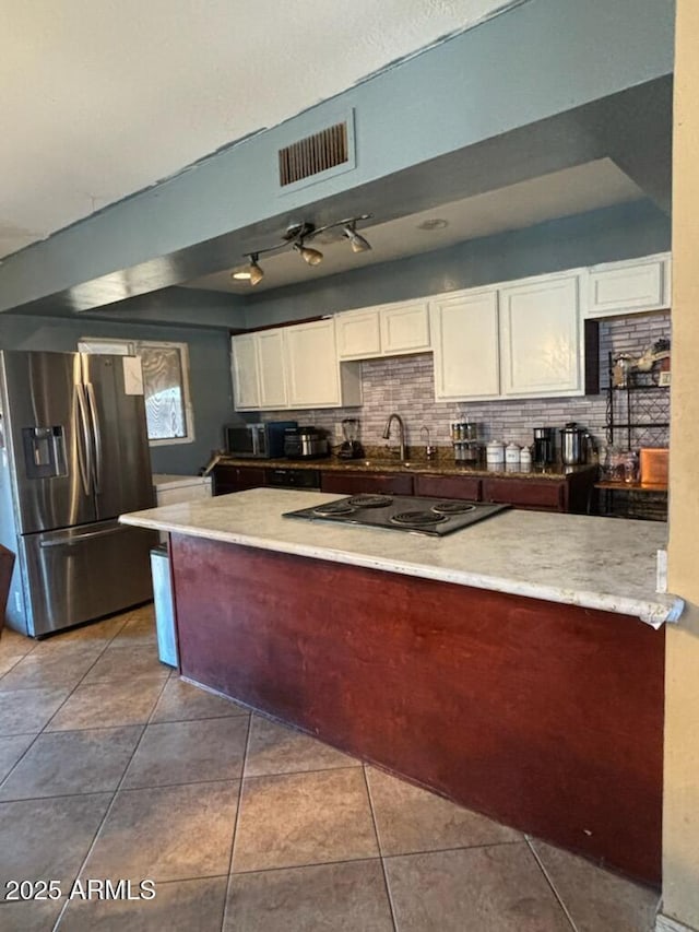 kitchen with stainless steel fridge with ice dispenser, white cabinets, black electric stovetop, a sink, and tile patterned flooring