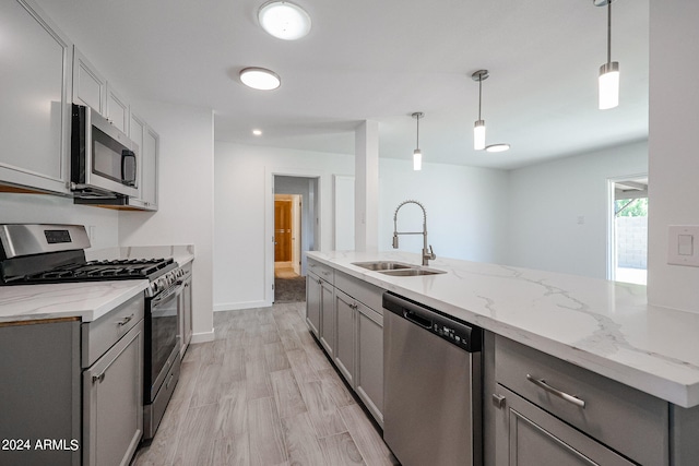 kitchen featuring gray cabinets, appliances with stainless steel finishes, sink, and light wood-type flooring