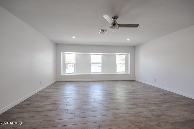 empty room featuring ceiling fan, a healthy amount of sunlight, and dark hardwood / wood-style floors