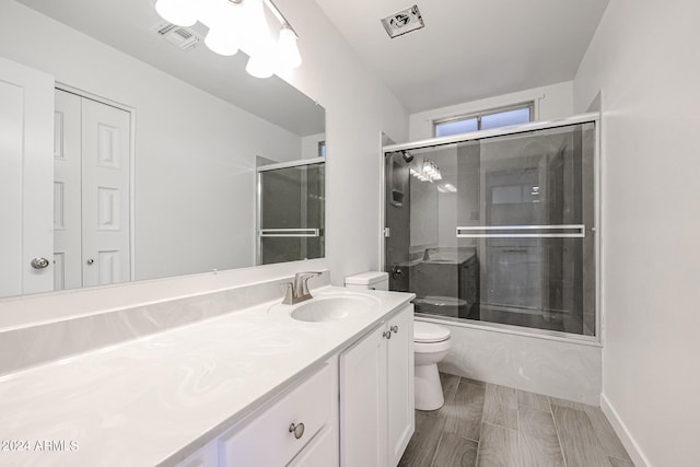 full bathroom featuring enclosed tub / shower combo, vanity, and toilet