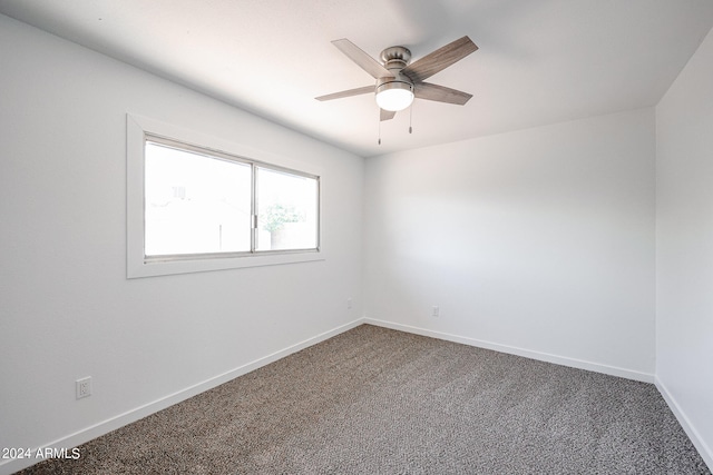 spare room with ceiling fan and dark colored carpet