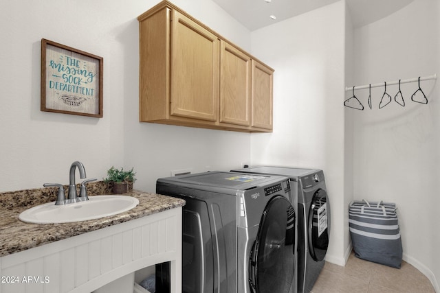 washroom with light tile patterned floors, independent washer and dryer, cabinet space, and a sink
