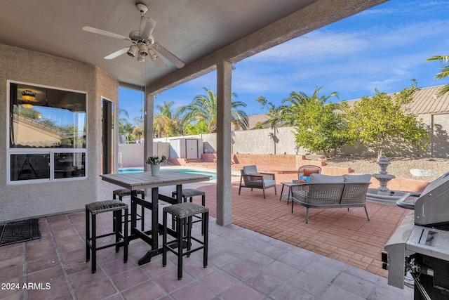 view of patio with an outdoor structure, a shed, a ceiling fan, an outdoor living space, and a fenced backyard