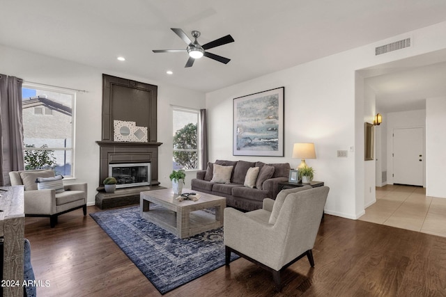 living room with visible vents, ceiling fan, a healthy amount of sunlight, and a glass covered fireplace