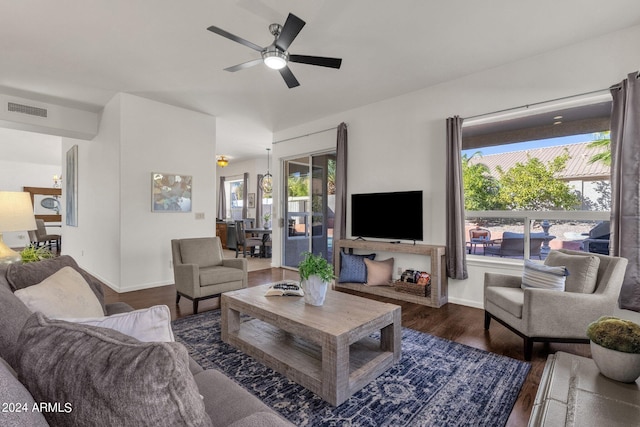 living room featuring a ceiling fan, visible vents, wood finished floors, and baseboards