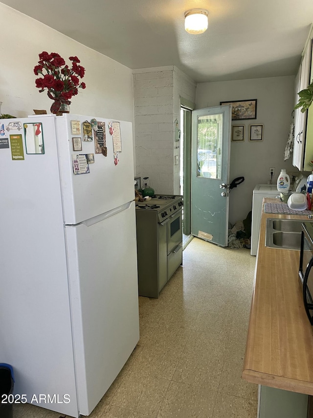kitchen featuring freestanding refrigerator, range with two ovens, light floors, and a sink