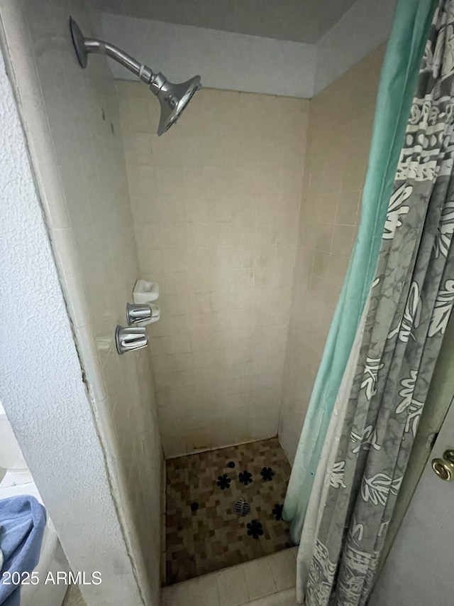 full bath with tiled shower and tile patterned floors