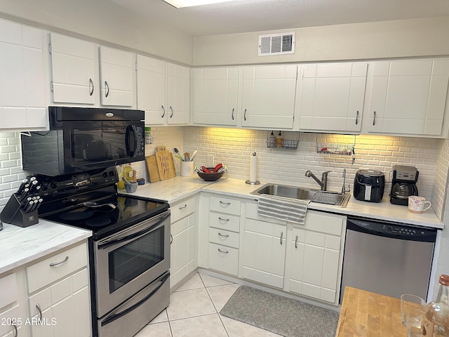 4201 E Camelback Rd Unit 51, Phoenix, AZ 85018 - kitchen with stainless steel appliances, a sink, tasteful backsplash, light tile patterned flooring, and white cabinetry