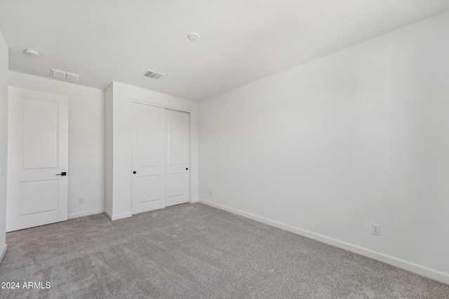 unfurnished bedroom with light carpet and a closet