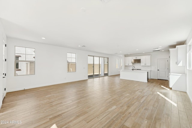 unfurnished living room with sink and light hardwood / wood-style flooring