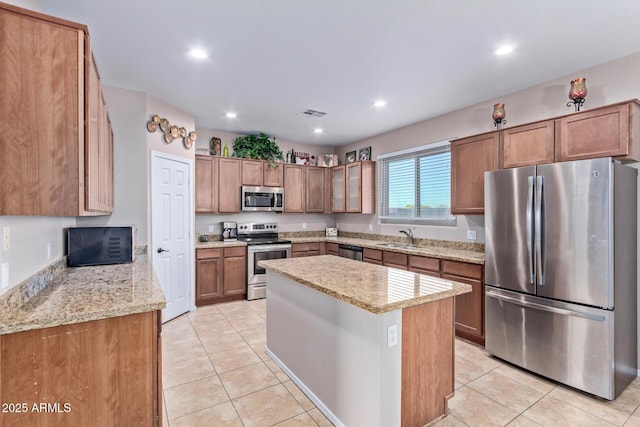 kitchen with light tile patterned flooring, sink, light stone counters, a center island, and stainless steel appliances