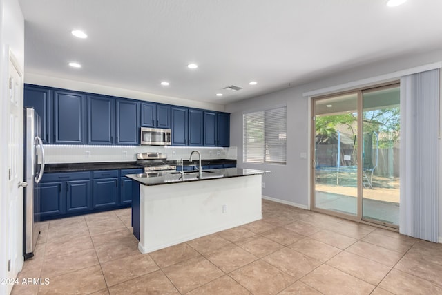 kitchen with blue cabinetry, appliances with stainless steel finishes, sink, and an island with sink