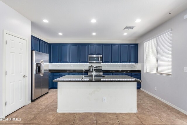 kitchen featuring appliances with stainless steel finishes, blue cabinets, and a kitchen island with sink