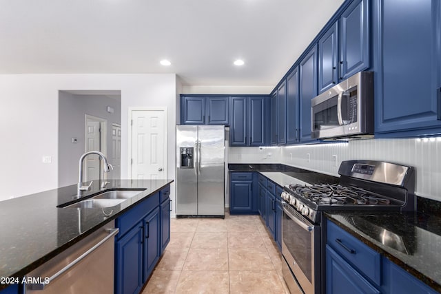 kitchen featuring sink, appliances with stainless steel finishes, blue cabinets, light tile patterned flooring, and dark stone counters