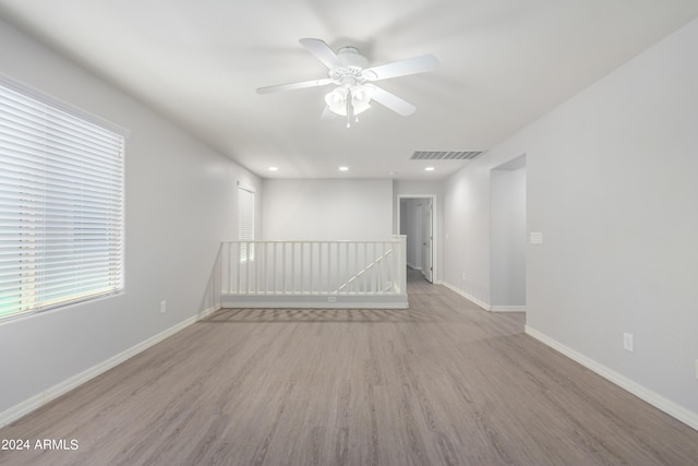 spare room with ceiling fan, a healthy amount of sunlight, and light wood-type flooring