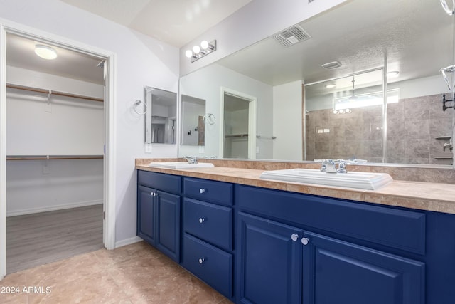 bathroom featuring vanity, a textured ceiling, and tiled shower