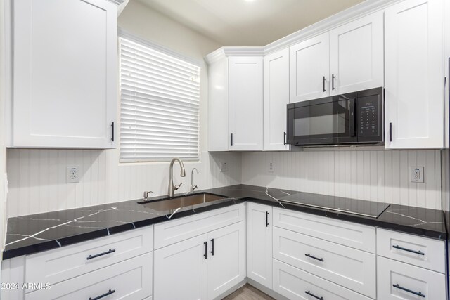 kitchen with white cabinetry, sink, black appliances, and dark stone countertops