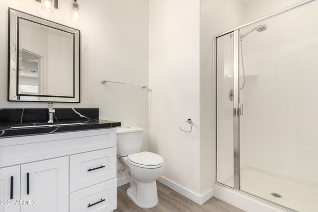 bathroom featuring vanity, toilet, a shower with door, and hardwood / wood-style floors