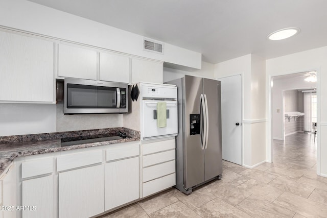 13842 N Tan Tara Dr, Sun City, AZ 85351 - kitchen featuring white cabinetry, stainless steel appliances, dark stone countertops, baseboards, and visible vents
