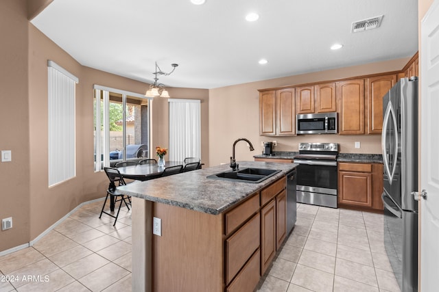 kitchen featuring a chandelier, sink, an island with sink, appliances with stainless steel finishes, and light tile patterned floors