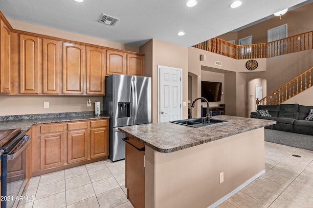 kitchen featuring light tile patterned flooring, stainless steel fridge with ice dispenser, a kitchen island with sink, and sink