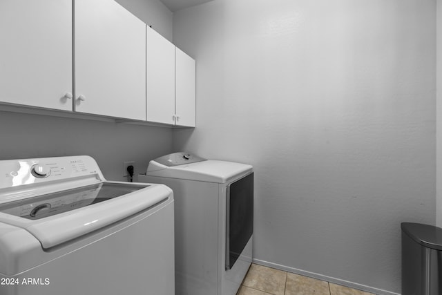 laundry area with washer and clothes dryer, cabinets, and light tile patterned floors