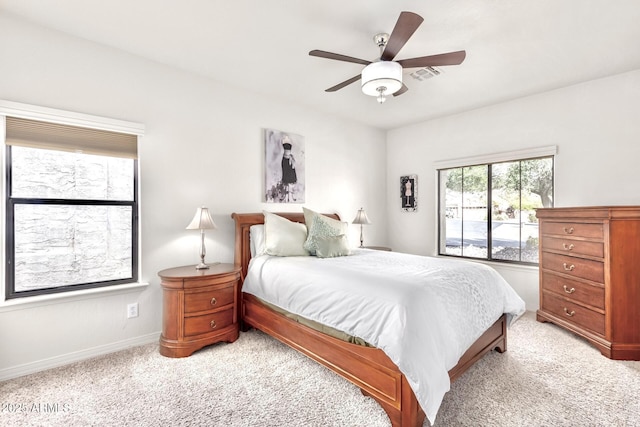 bedroom featuring visible vents, baseboards, light colored carpet, and a ceiling fan