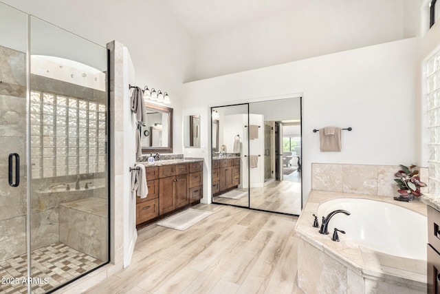 bathroom with vanity, a garden tub, wood finished floors, and a shower stall