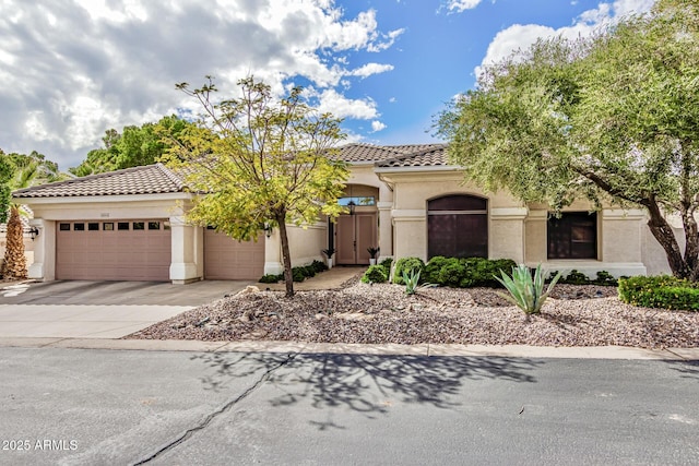 mediterranean / spanish home with concrete driveway, a tiled roof, an attached garage, and stucco siding