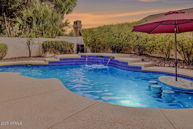 pool at dusk featuring a fenced backyard and a fenced in pool