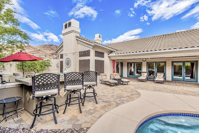 view of patio / terrace with an outdoor kitchen, french doors, and outdoor dry bar