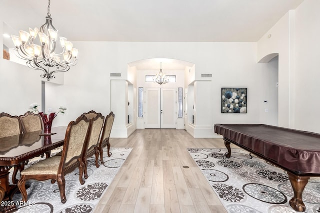 entryway featuring arched walkways, a notable chandelier, light wood-style flooring, and visible vents