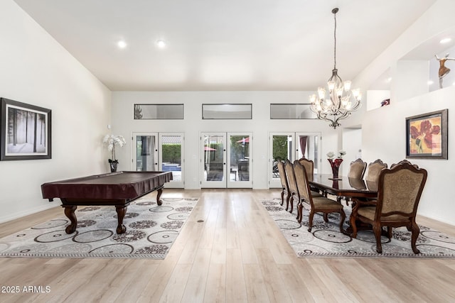 dining area featuring wood finished floors, a notable chandelier, french doors, and a towering ceiling