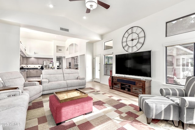 living room with visible vents, high vaulted ceiling, light wood-type flooring, and a ceiling fan