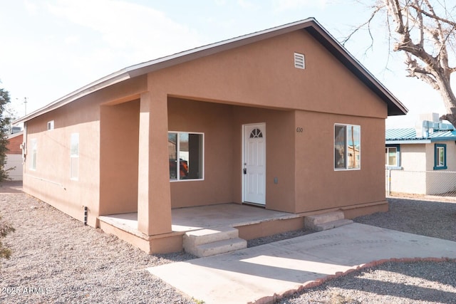 view of front facade with a patio, fence, and stucco siding