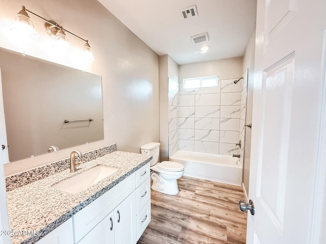 full bath featuring visible vents, toilet, wood finished floors, vanity, and shower / washtub combination