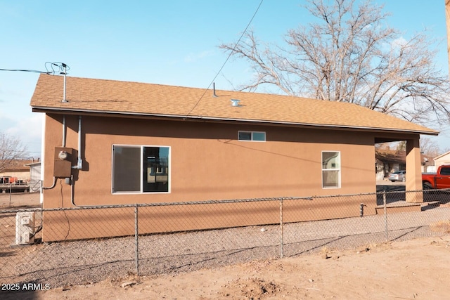 view of property exterior featuring roof with shingles, fence, and stucco siding