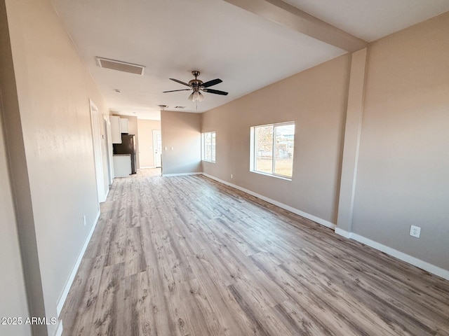 empty room with light wood-style flooring, visible vents, ceiling fan, and baseboards