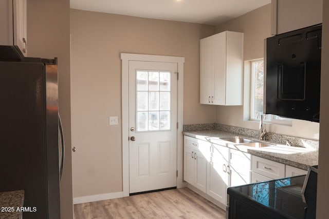 kitchen with white cabinetry, a sink, and freestanding refrigerator