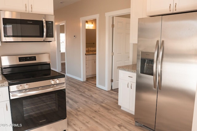 kitchen with stainless steel appliances, light wood-type flooring, white cabinetry, and light stone countertops