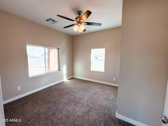 carpeted spare room with a ceiling fan, plenty of natural light, visible vents, and baseboards