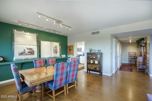 dining room with track lighting, concrete floors, visible vents, and baseboards