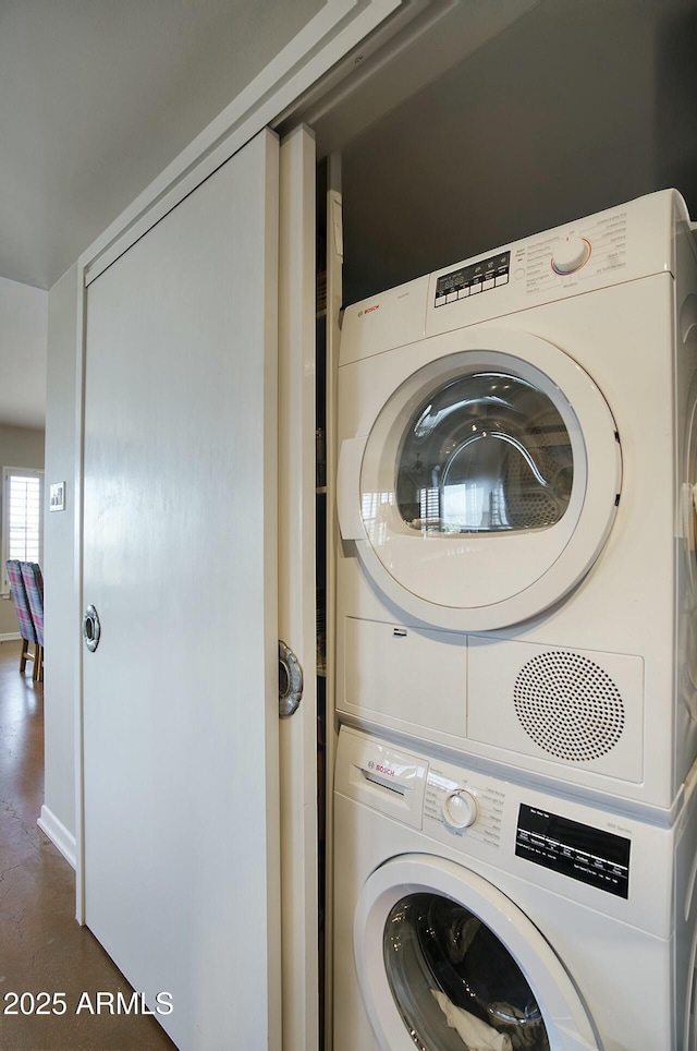 clothes washing area featuring stacked washer and dryer and laundry area