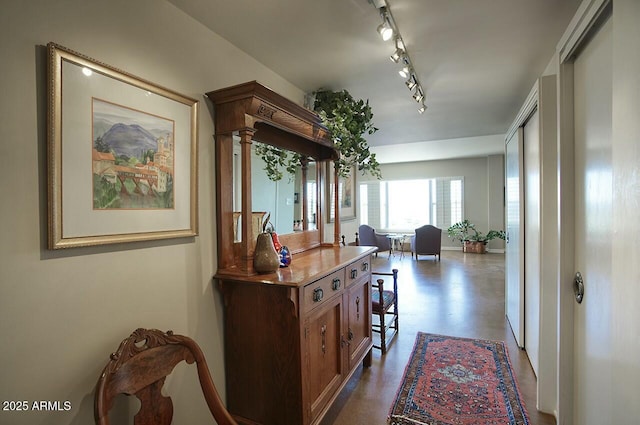 hall featuring rail lighting, finished concrete flooring, and ornate columns