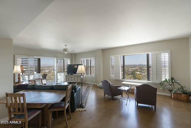 dining space with ceiling fan, concrete floors, and baseboards