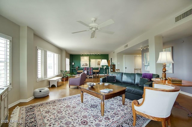 living area featuring ceiling fan, visible vents, and baseboards